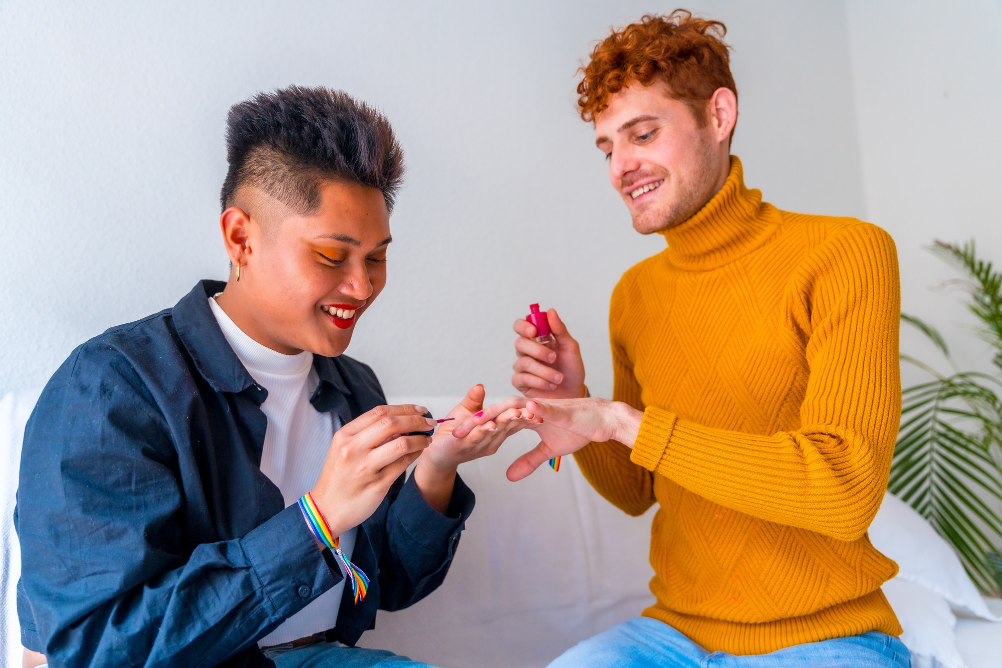 Beautiful gay couple putting on makeup, painting their nails and smiling being romantic